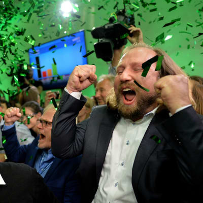 Glada människor firar på det tyska gröna partiets valvaka i Bayern. Över dem regnar det grönt konfetti