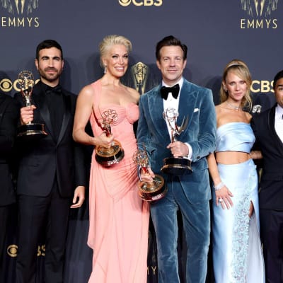 Ett gäng skådespelare poserar på röda mattan och håller i Emmystatyetter medan de ler.