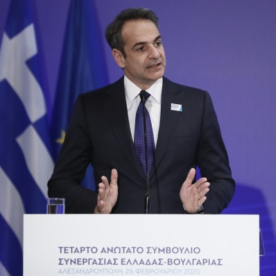 Greklands premiärminister Kyriakos Mitsotakis håller tar vid ett podium. Bakom honom ser man en EU-flagga och Greklands flagga.