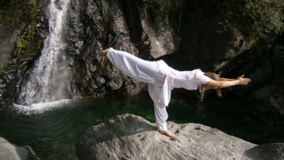 En kvinna som utför yoga på en klippa.