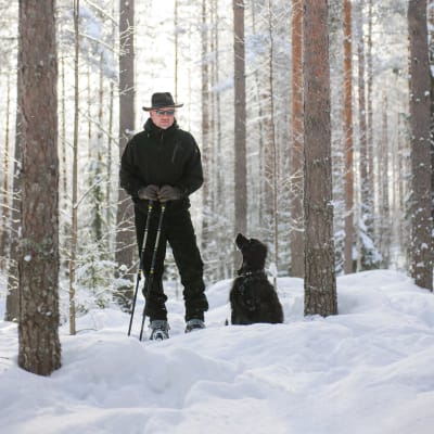 Jyväskyläläinen Timo Akselin lumisessa metsässä koiransa kanssa.