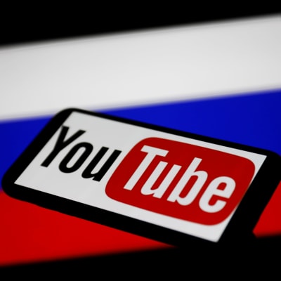 Youtuben logo älypuhelimessa. Takana näkyy Venäjän lippu.