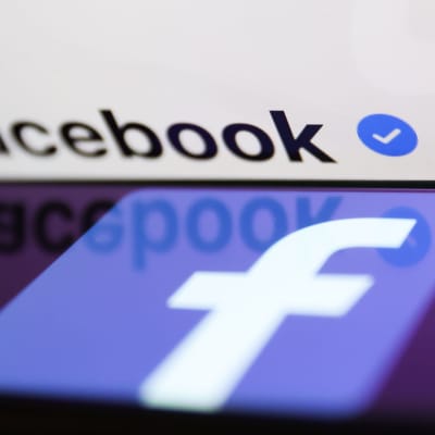 Facebookin tunnus puhelimen näytöllä ja sininen varmennusmerkki. 