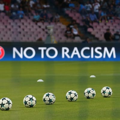 Säg nej till rasism på en fotbollsarena med bollar i förgrunden