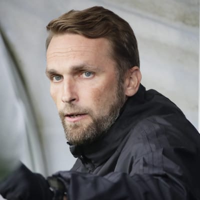 Jalkapallovalmentaja Jani Honkavaara istuu vaihtopenkillä ottelussa.