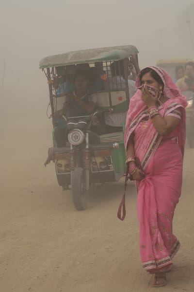 Kvinna försöker skydda sig mot luftföroreningar i New Delhi i Indien.