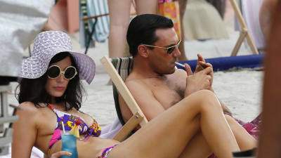 Jon Hamm och Jessica Pare ligger på stranden i tv-serien Mad Men. 