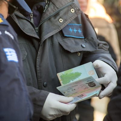 Grekisk polis granskar flyktingars id-handlingar.