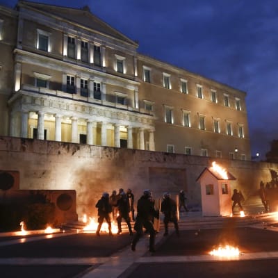 Demonstranter kastar brandbomber mot polisen utanför det grekiska parlamentet.