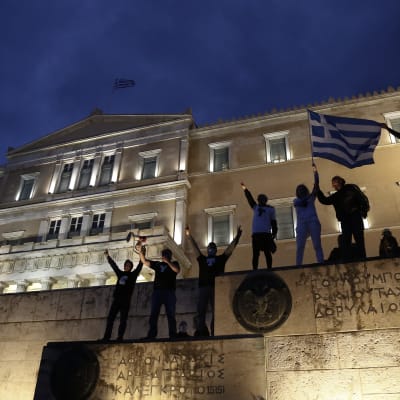 Människor viftar med den grekiska flaggan utanför parlamentsbyggnaden.