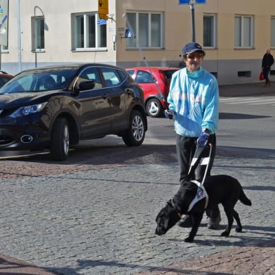 Maja Lindroos med sin ledarhund väntar för att ta sig över cykelväg.