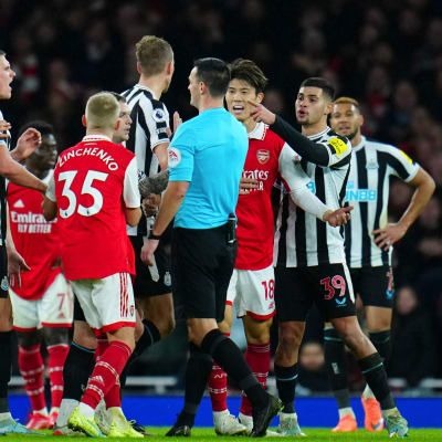 Spelare från Arsenal och Newcastle omringar domaren.