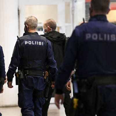 Poliiseja menossa turvasaliin jossa käsiteltiin katujengiläisten suunnittelemaa joukotappelua, Helsingin käräjäoikeudessa.