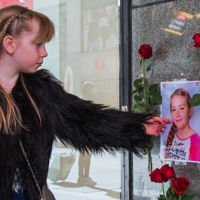 Flicka bredvid ett foto av ett av offren för terrorangreppet på Drottninggatan 2017.