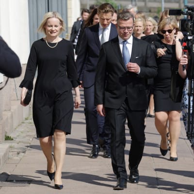 Petteri Orpo, Riikka Purra och de övriga ministrarna går på en gata.