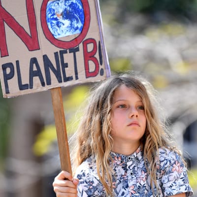 Liten flicka på en mans axlar håller i en skylt med texten "There is NO planet B".