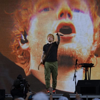 Ed Sheeran på scen med en bild av Ed Sheeran på storskärm bakom honom.