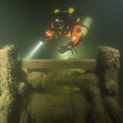 Sukeltaja tutkii Sipoon vesiltä löydetyn lähes täydellisesti säilyneen siipiratashinaajan hylyn ankkuripeliä