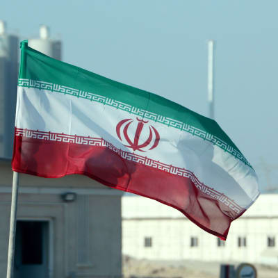 Irans flagga vajar framför iranskt kärnkraftverk.