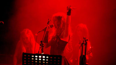Indica-yhtye esiintyy punaisessa valossa. Etualalla laulaja Jonsu mikrofoni kädessä, toinen käsi ilmassa.