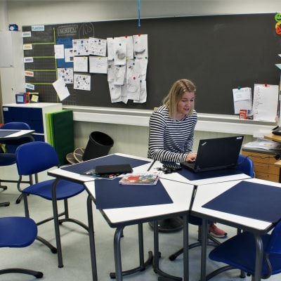 Jasmin Bilenberg sitter i ett tomt klassrum och håller distansundervisning med hjälp av en dator.
