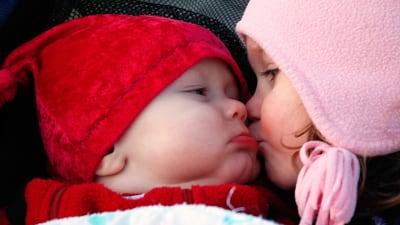 Barn som pussar en bebis.