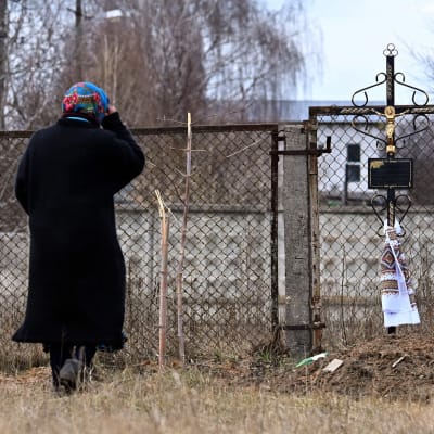 En kvinna korsar sig inför en massgrav i Ukraina.