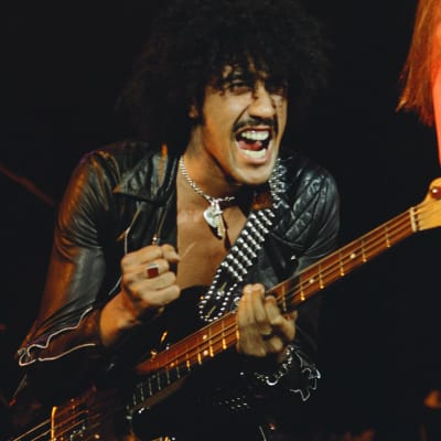 Phil Lynott mustassa nahkaasussa lavalla basso kädessä.