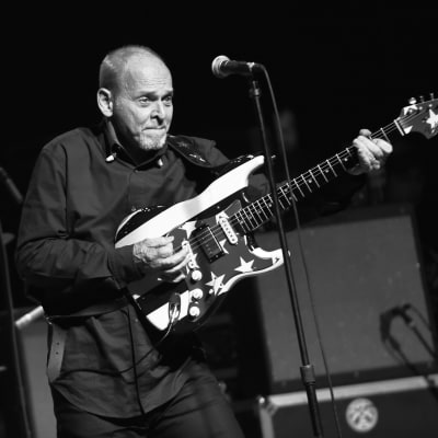 Svartvit bild på Wayne Kramer som spelar gitarr på scen.