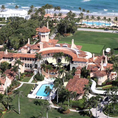 En enorm lyxvilla med pool och palmer överallt. I övre kanten skymtar havet.