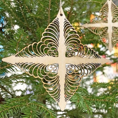 En Tomasstjärna, ett modernt fanerkors som liknar det gamla Tomaskorset med många krusiduller, hänger i en grön julgran.