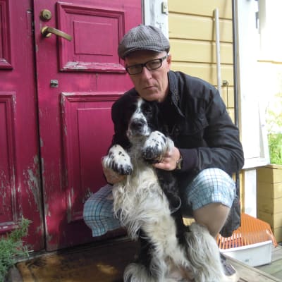 Tom Ridberg poserar i keps med en svarvit hund. 