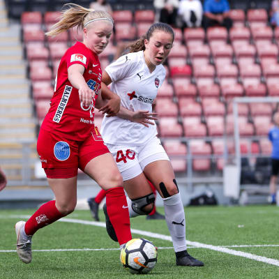 Rebecka Mannström iklädd röd spelardräkt kämpar om bollen under en fotbollsmatch.