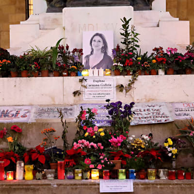 Blommor och ljus har lagts ner vid en bild på bloggaren Daphne Caruana Galizia som mördades med en bilbomb.