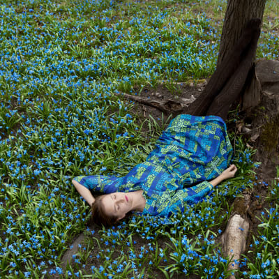 Wilma Hurskaisen teos Blue: Nainen makaa maassa skillojen keskellä