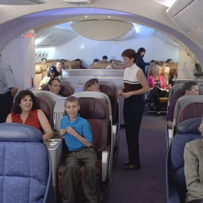 Boeing 787 Dreamliner -lentokoneen mallimatkustamo, jossa on ihmisiä ja henkilökuntaa.