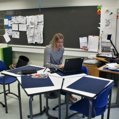 Jasmin Bilenberg sitter i ett tomt klassrum och håller distansundervisning med hjälp av en dator.