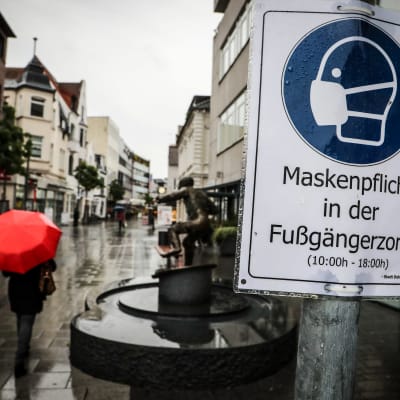 En skylt med texten "ansiktsskyddsplikt" på tyska