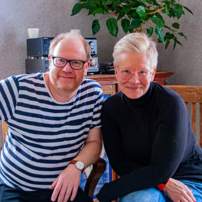 En man och en kvinna sitter på varsin stol och ler mot kameran