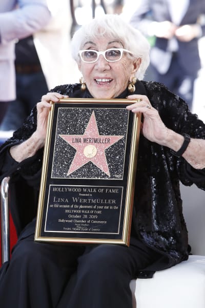 Lina Wertmüller håller upp ett Holllywood Walk of Fame-plakat med hennes namn i en stjärna.
