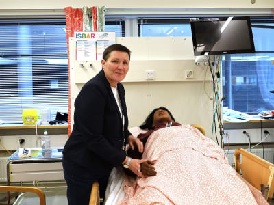 Maria Forss rättar till handen på en övningsdocka i en sjukhussäng.