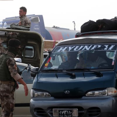 Beväpnade män vakar över irakier som flytt våldet i staden Mosul.