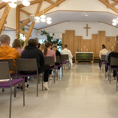 Skriftskolelver ber i en kyrka.