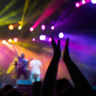 Ihminen heiluttaa käsiään konserttiyleisössä.