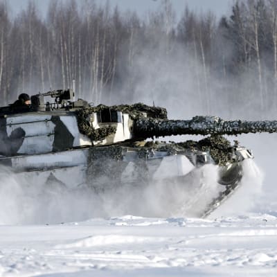 En Leopard-stridsvagn kör framåt i snön.