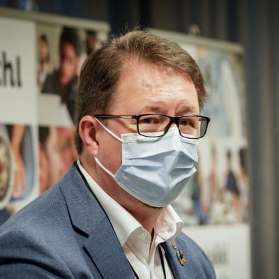 Mika Salminen iförd munskydd under en presskonferens.