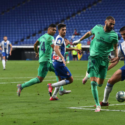Karim Benzema syöttää pallon Casemirolle Espanyol-puolustajan jalkojen välistä.  