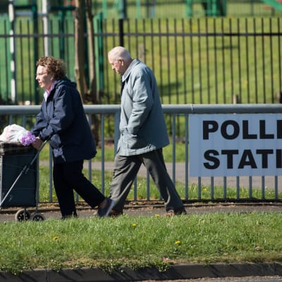 Ett äldre par passerar en vallokal i Manchester, norra England 4.5.2017