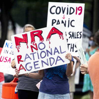 Mielenosoittajat pitelevät NRA:ta ja aseita vastustavia kylttejä.