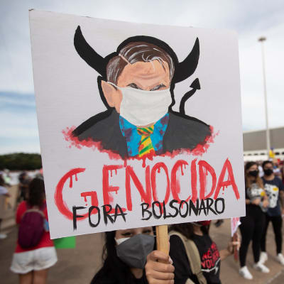 Demonstrationer i Brasilien håller upp en skylt där det står "folkmord Bolsenaro".